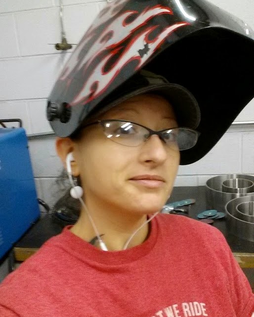Sarah Cornett in a shop, welding helmet flipped up