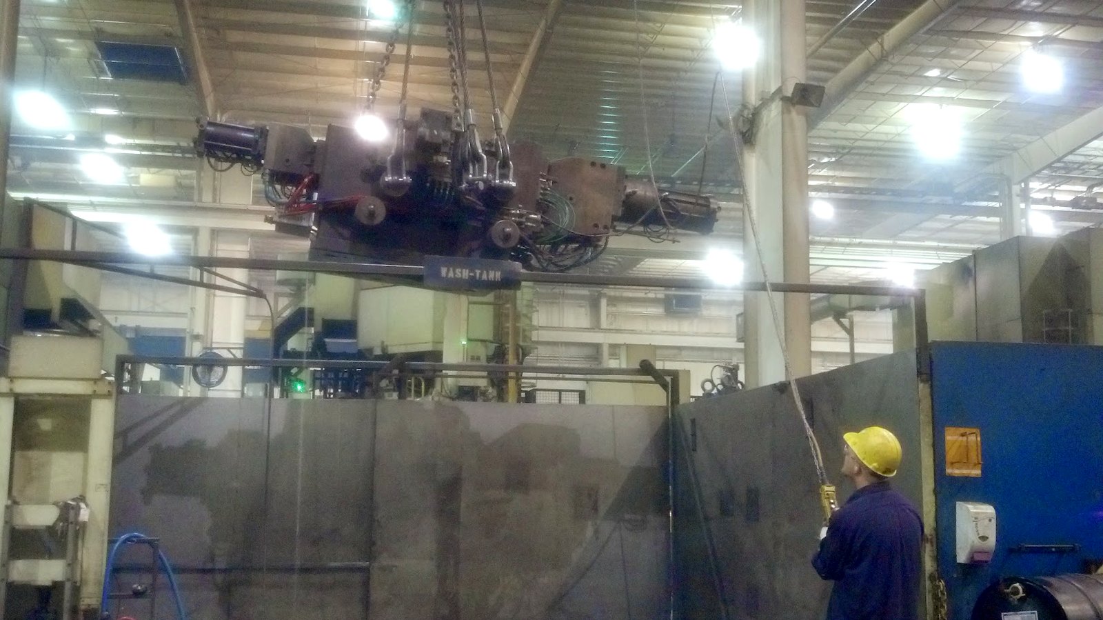 A working shop bay with an overhead crane and a welder at the far end